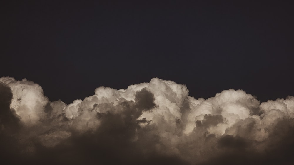 a plane flying through a cloud filled sky