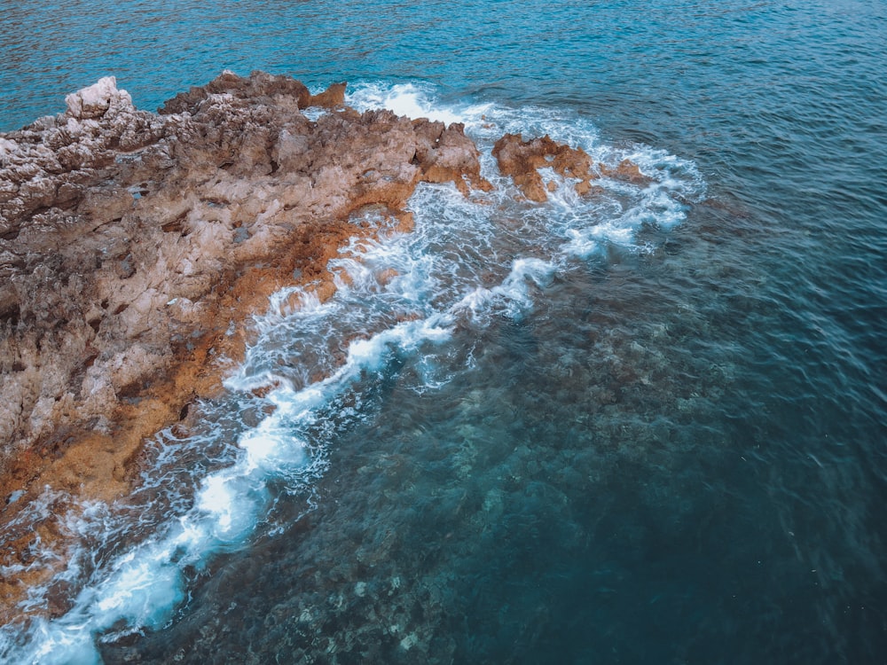 an aerial view of the ocean with waves crashing on the rocks