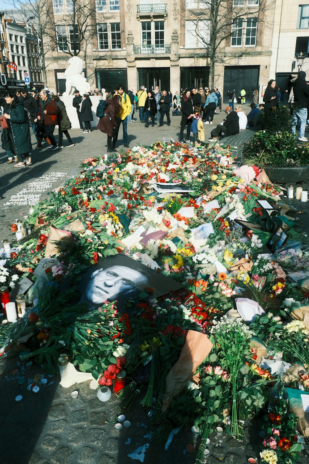 um grupo de pessoas em pé ao redor de uma pilha de flores