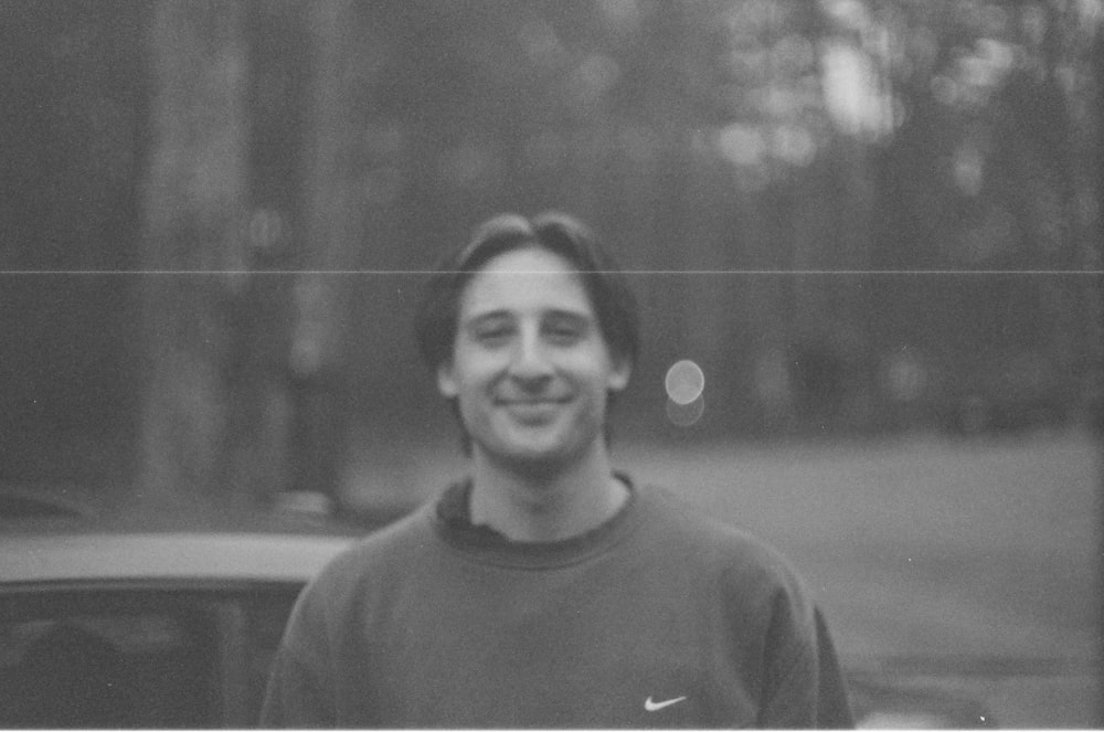 a black and white photo of a man in front of a car