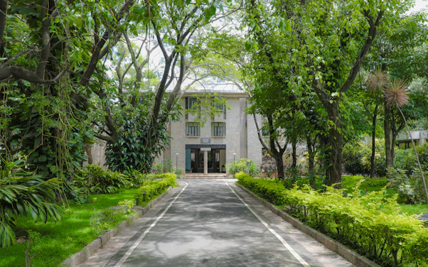 a large white building surrounded by lush green trees