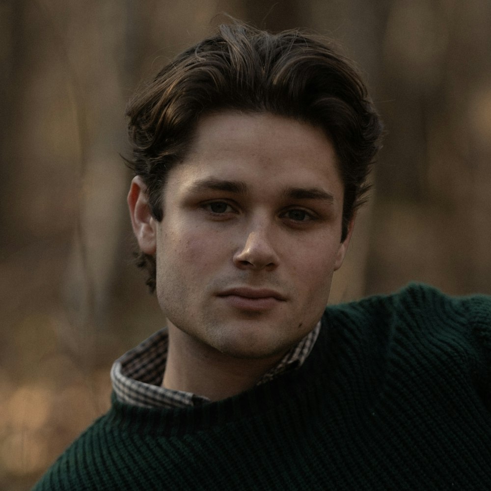 Un hombre con un suéter verde posando para una foto