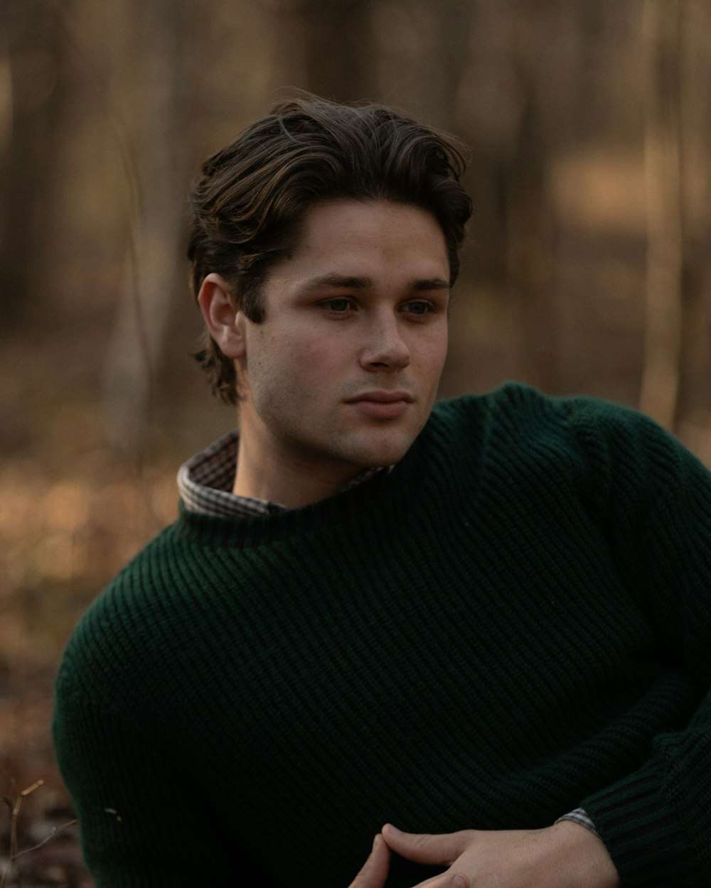 숲 속에 앉아 있는 초록색 스웨터를 입은 남자