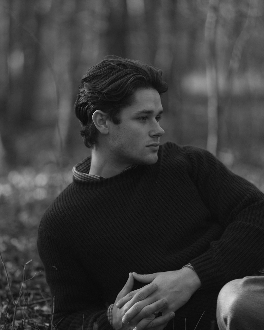 a man sitting on the ground in the woods