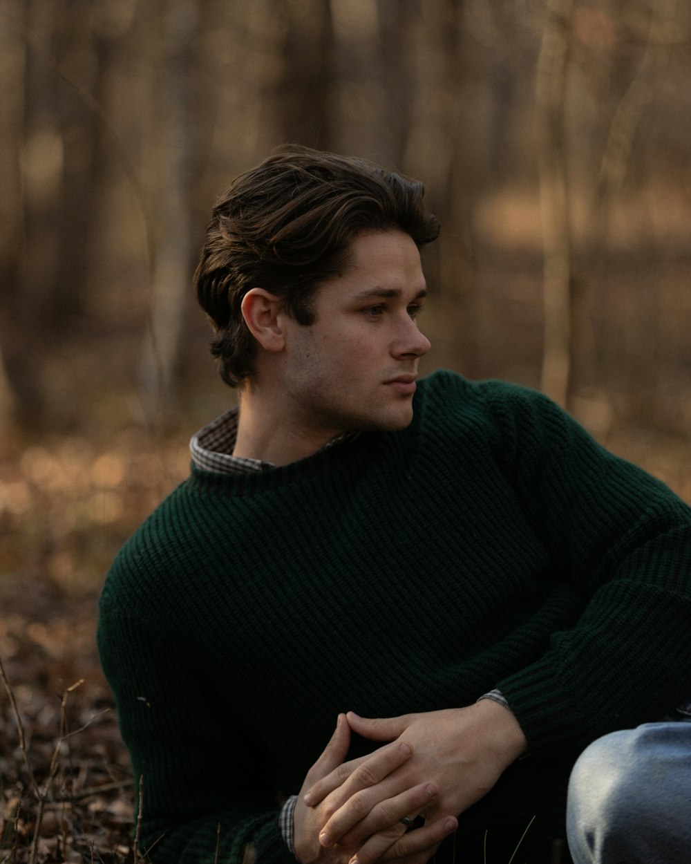 森の中に座る緑のセーターを着た男