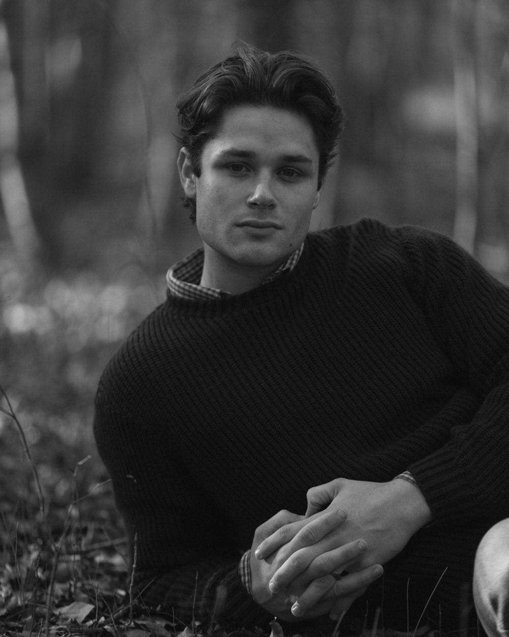 a black and white photo of a man sitting in the woods