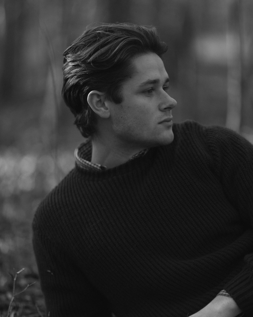 a man sitting on the ground in the woods