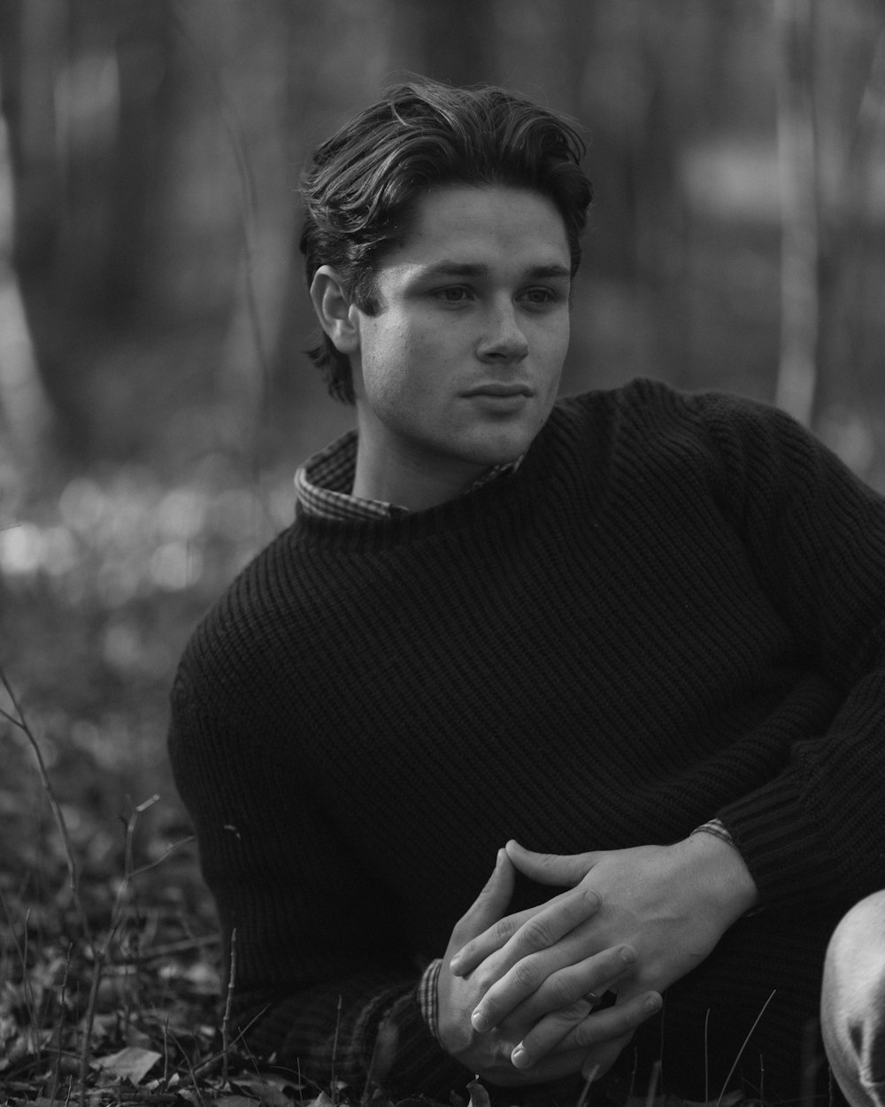 a man sitting on the ground in the woods