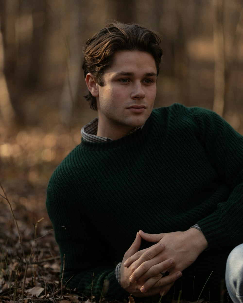 a man in a green sweater sitting on the ground