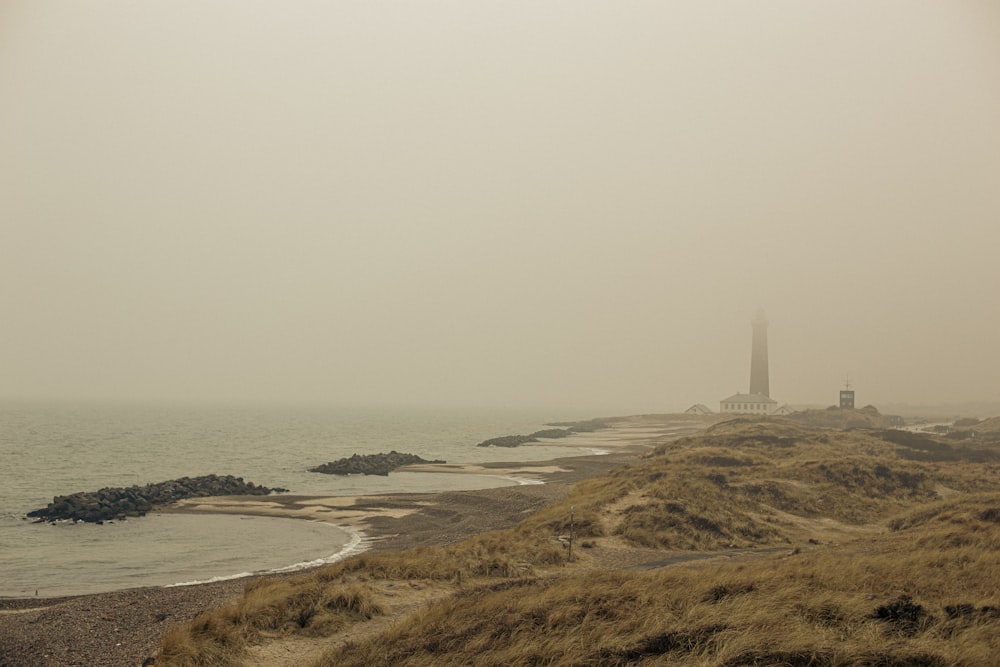 Ein nebliger Strand mit einem Leuchtturm in der Ferne