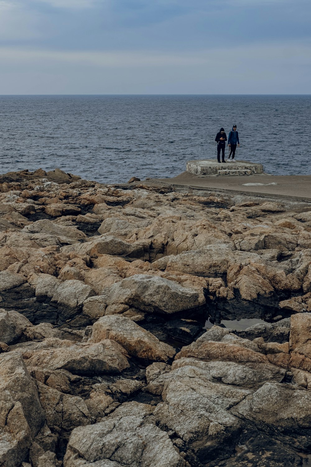 a couple of people standing on top of a rocky beach