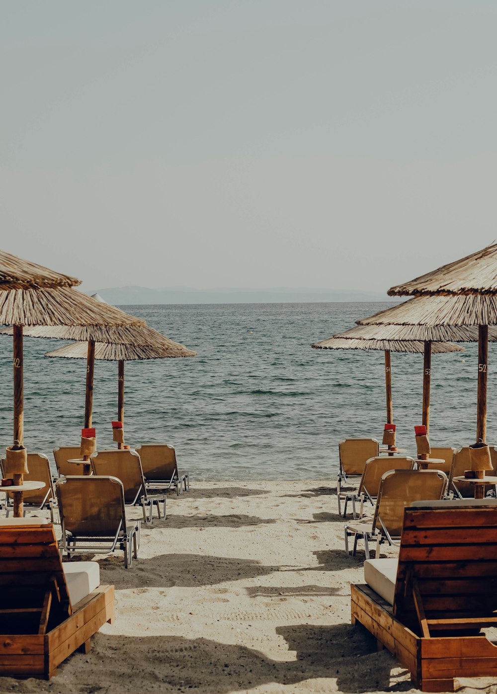 chairs and umbrellas on the beach with the ocean in the background