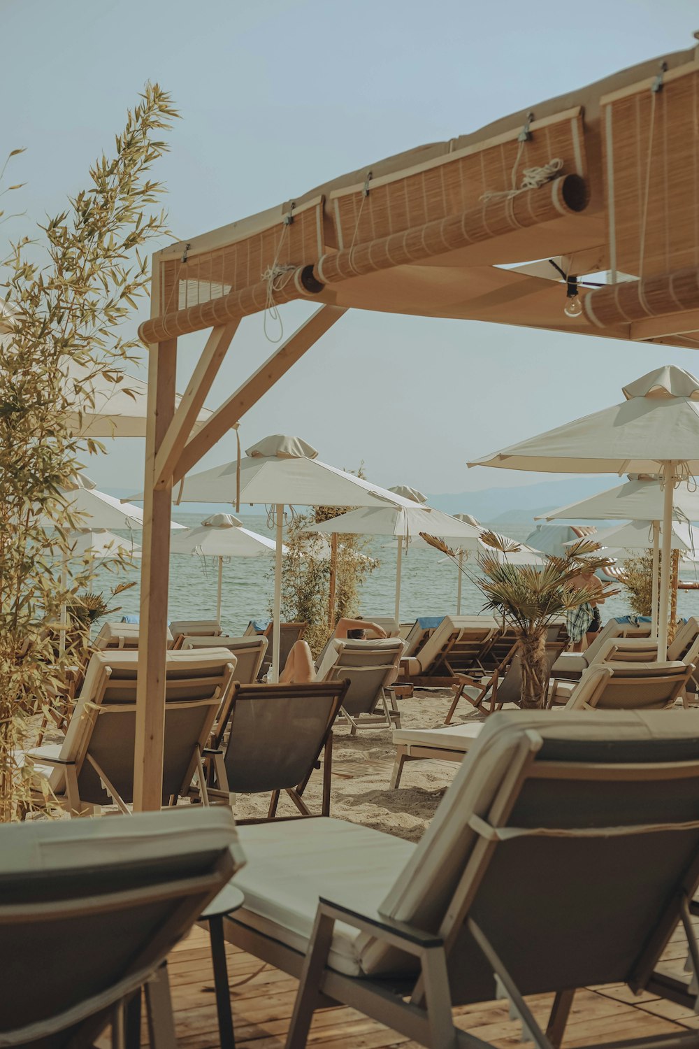 chairs and umbrellas on a wooden deck near the ocean