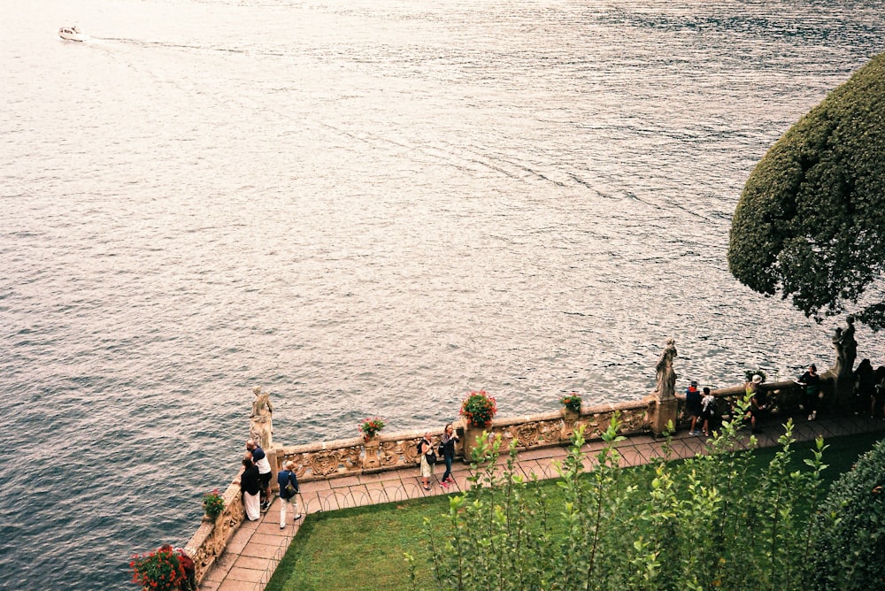 a group of people walking down a walkway next to a body of water