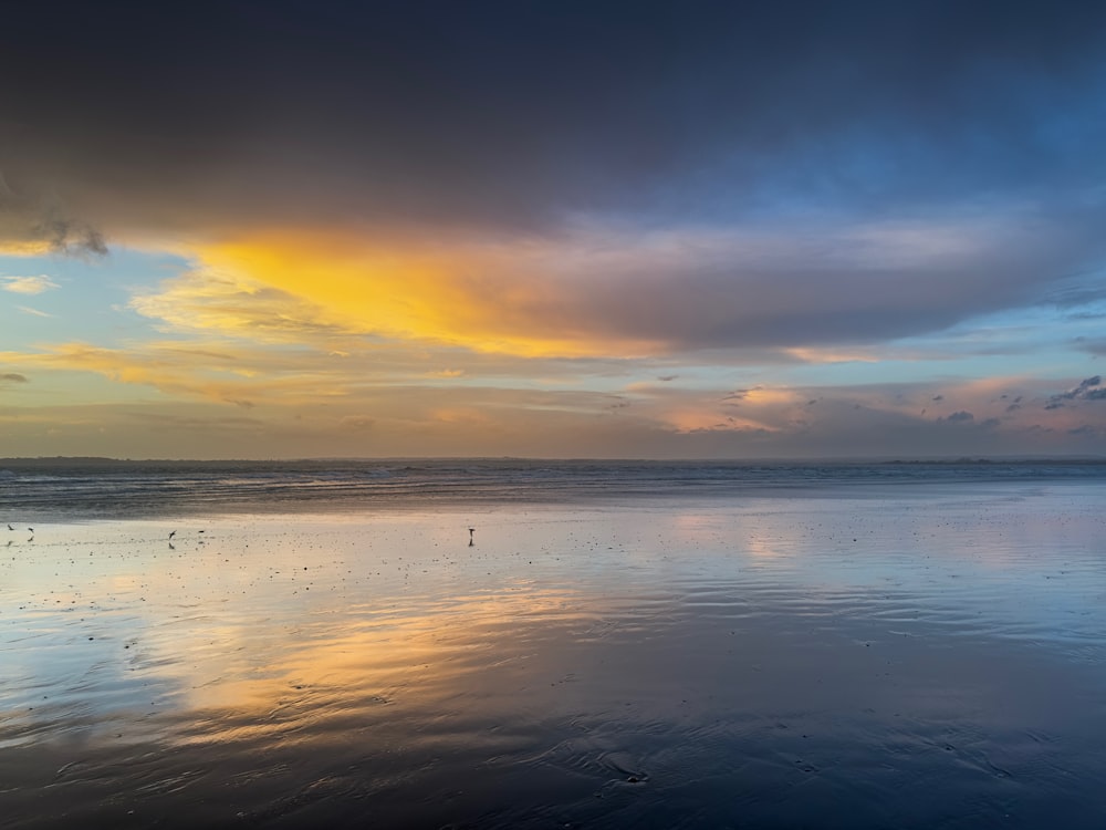 the sky is reflected in the wet sand on the beach