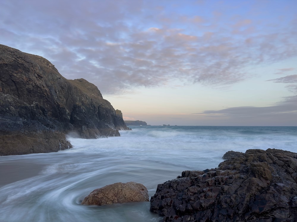 a large rock sitting on top of a beach next to the ocean