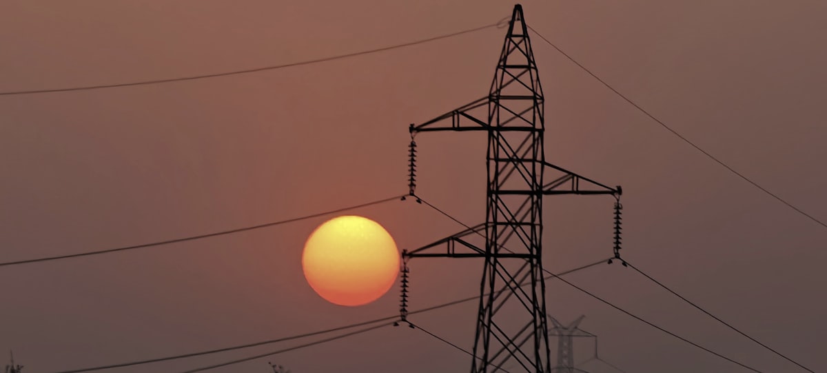 Power transmission lines silhouetted against a colorful sunset sky, representing America's electrical grid infrastructure