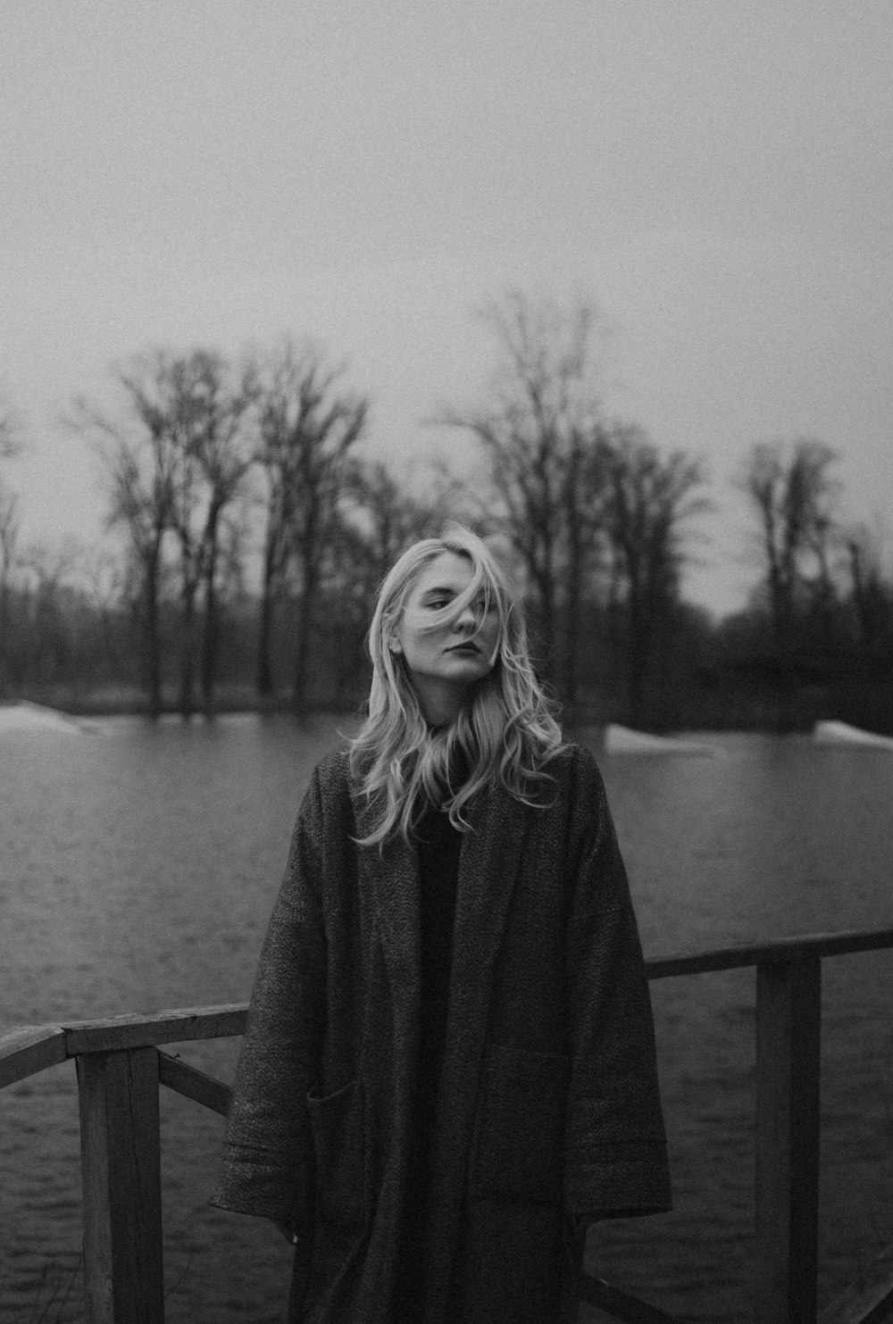 a black and white photo of a woman standing on a bridge