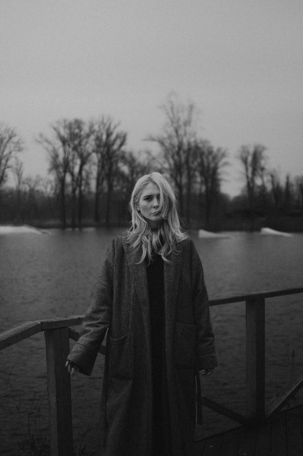 a woman standing on a bridge near a body of water