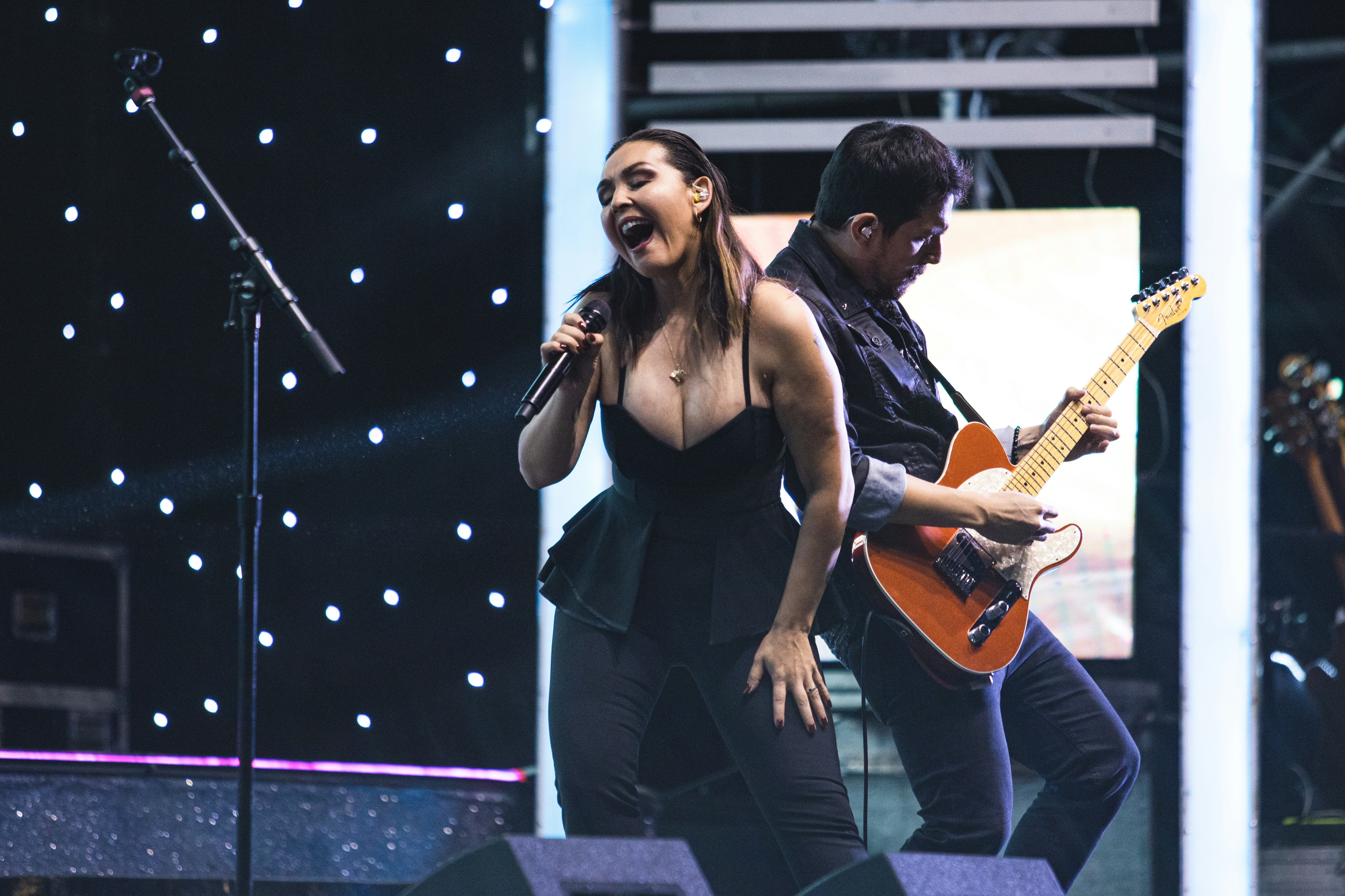 seorang wanita bernyanyi ke mikrofon sambil memegang gitar