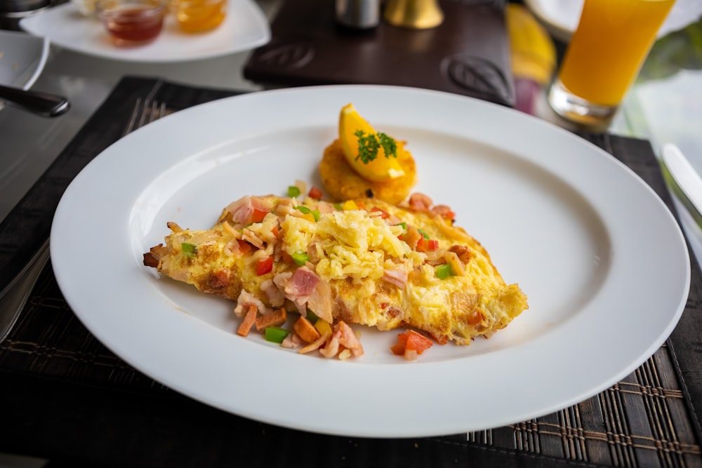 a white plate topped with an omelet next to a glass of orange juice