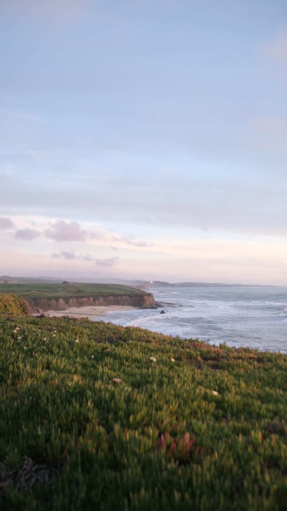 a view of the ocean from a grassy hill