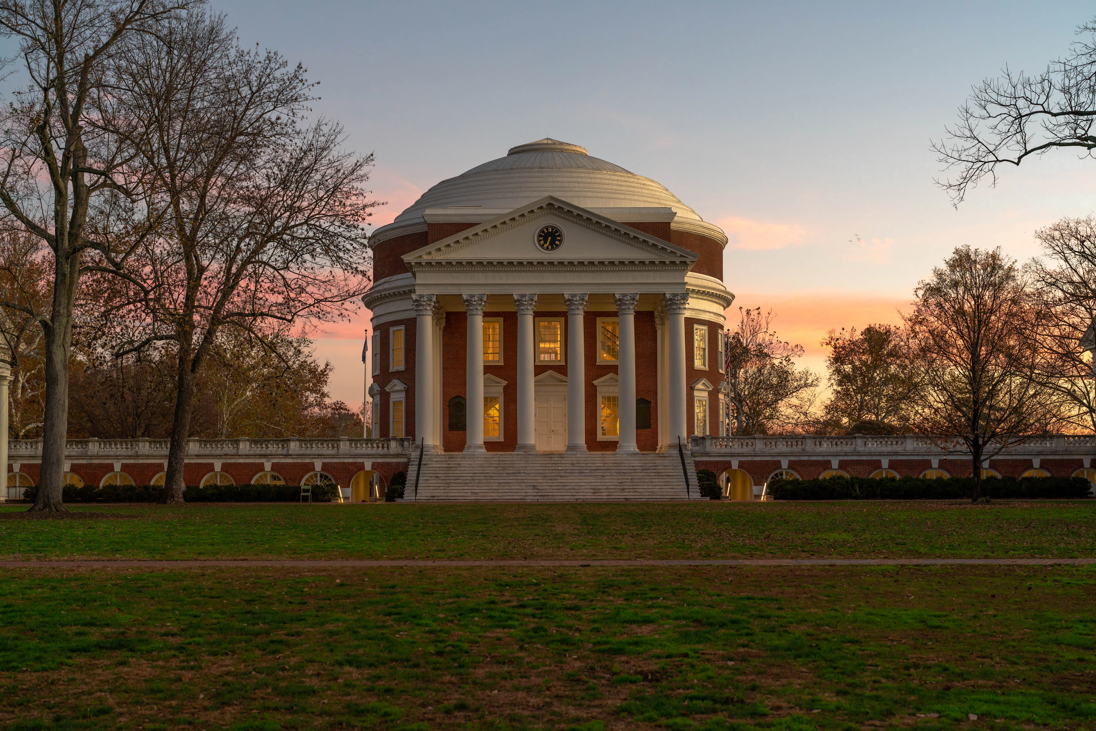 Domed university building at dusk over a lawn