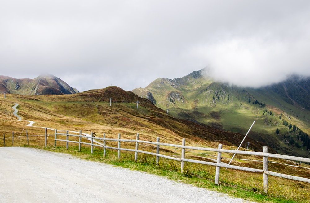 a wooden fence on a dirt road in the mountains