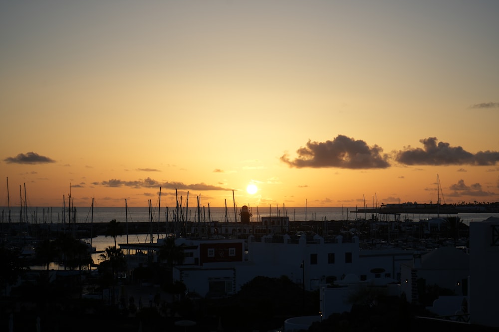 the sun is setting over a harbor with sailboats