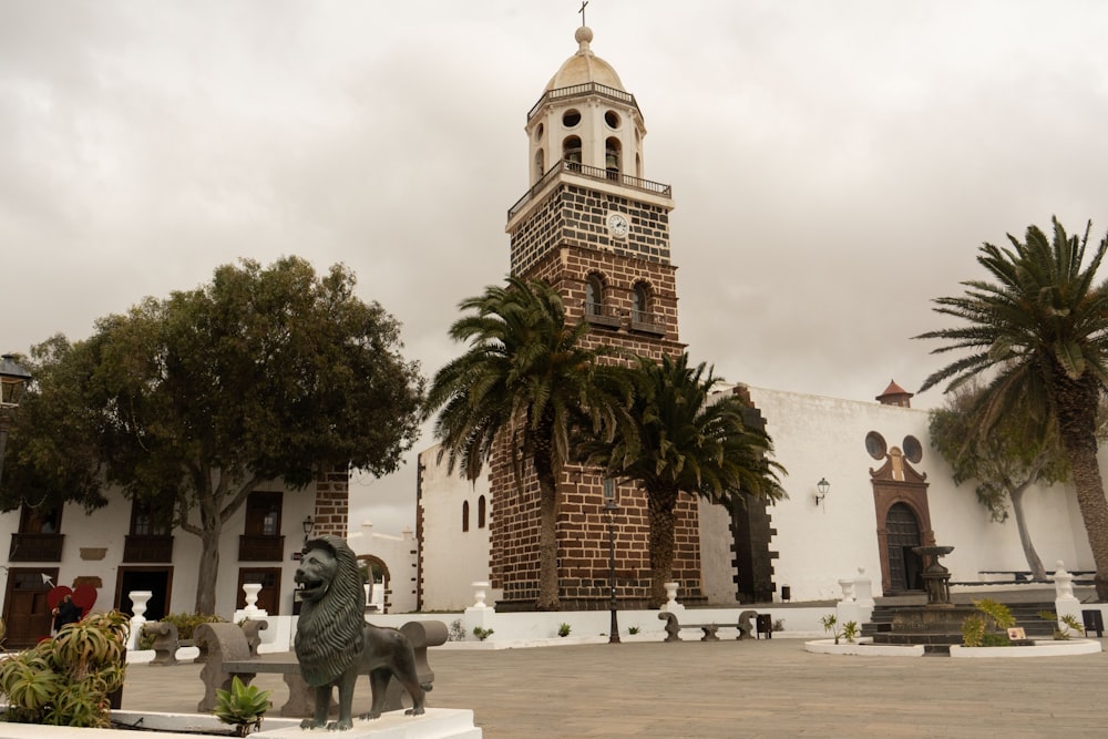 a clock tower with a statue of a lion in front of it