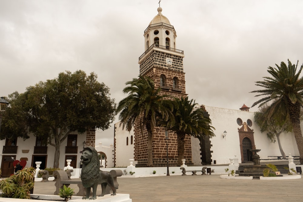 una torre del reloj con una estatua de un león frente a ella