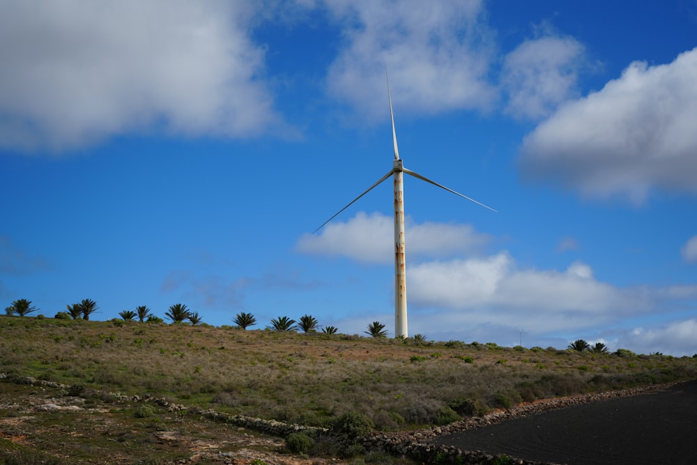 a wind turbine sitting on top of a lush green hillside