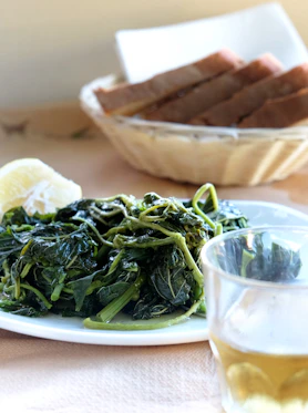 a plate of greens next to a glass of wine