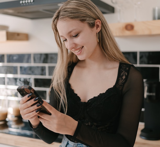 a woman standing in a kitchen looking at her cell phone