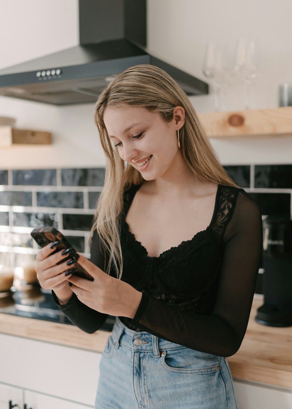 eine Frau, die in einer Küche steht und auf ihr Handy schaut