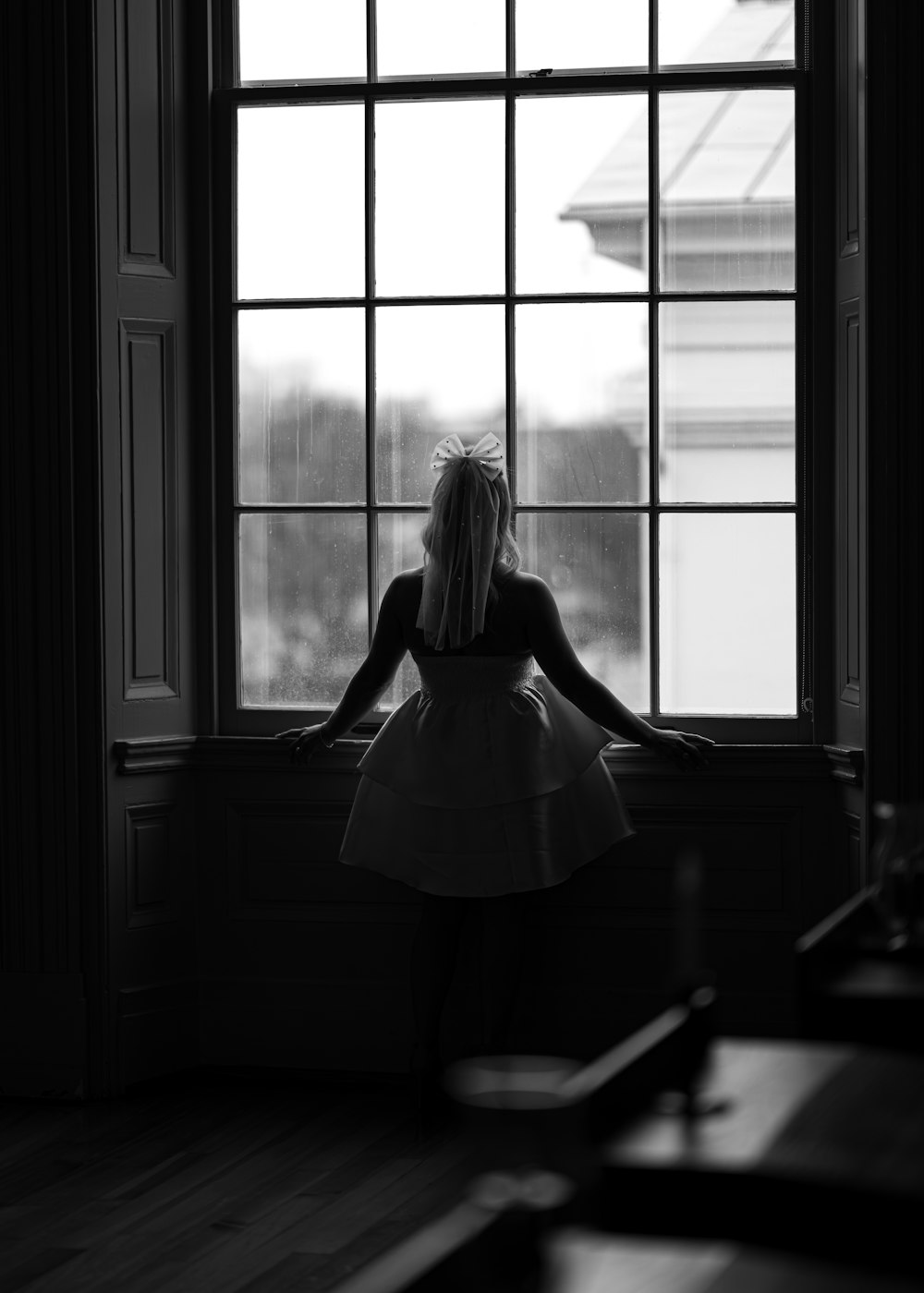 uma mulher em pé em frente a uma janela