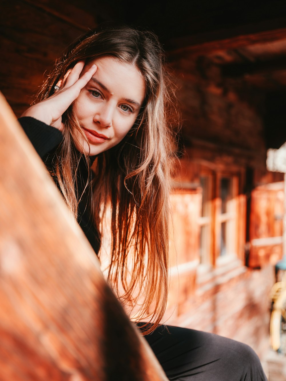 a beautiful young woman sitting on top of a wooden bench