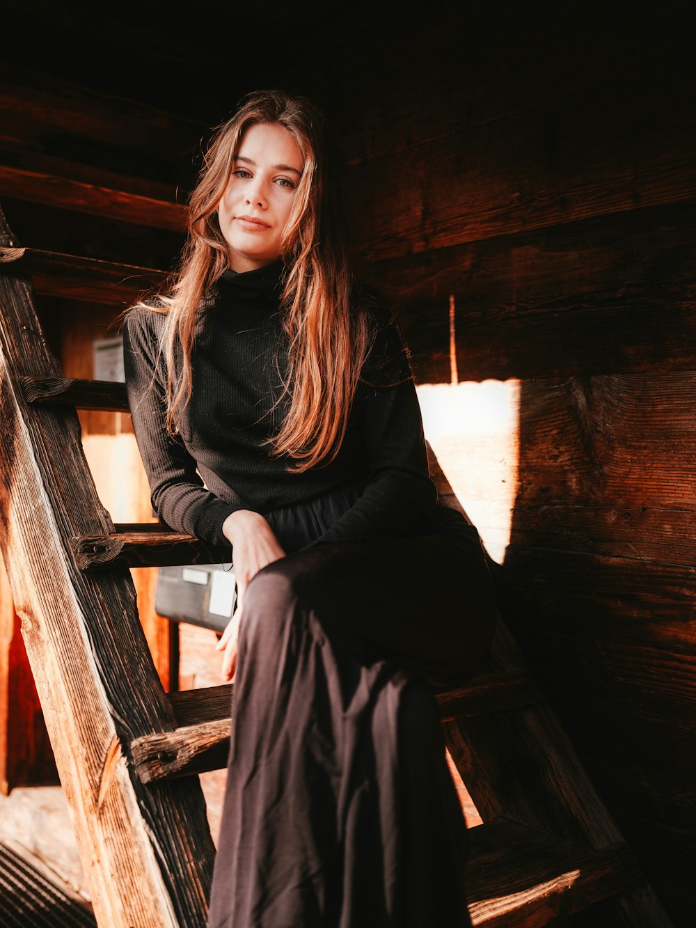 a woman sitting on top of a wooden ladder