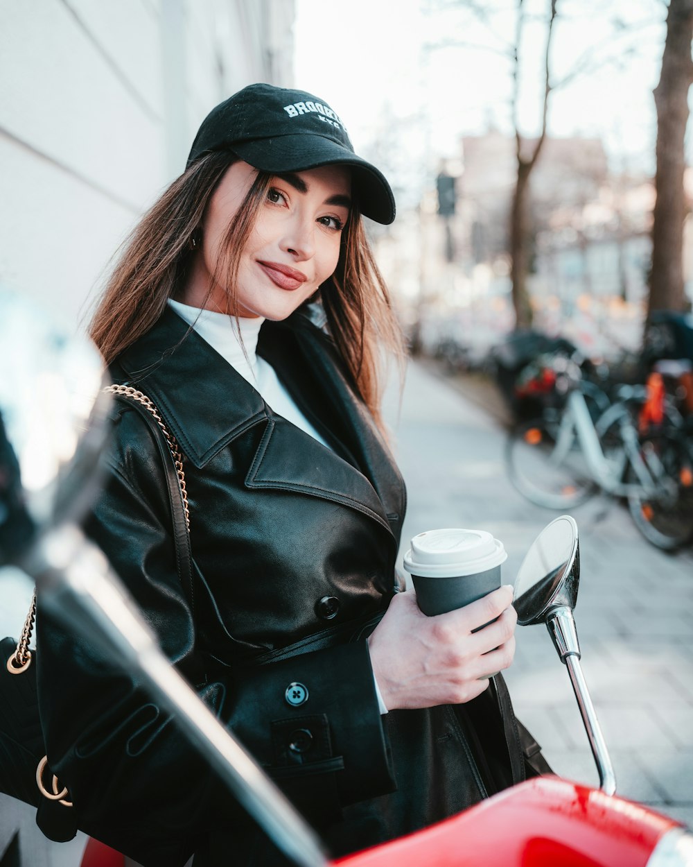 a woman in a black leather jacket holding a coffee cup