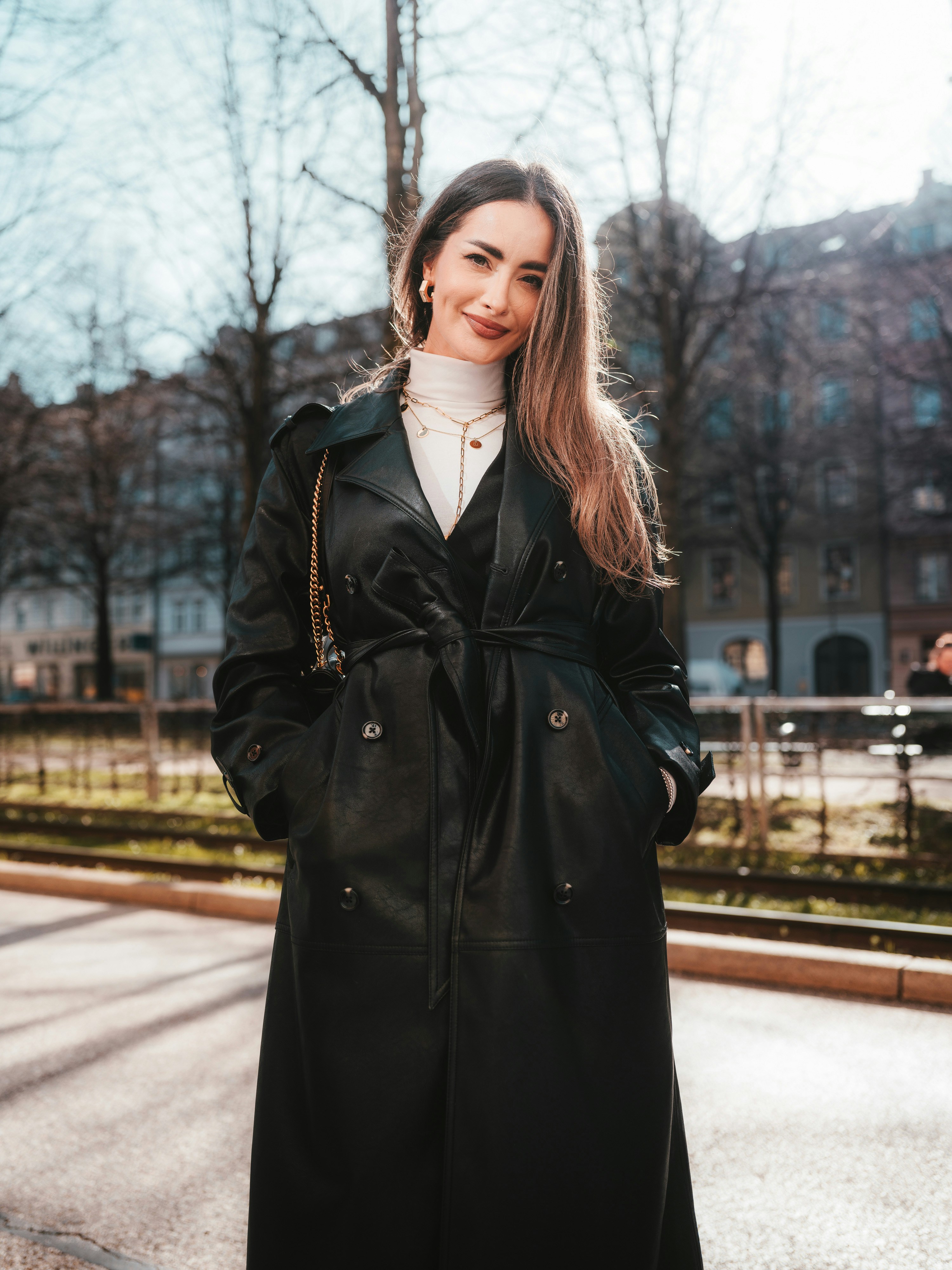 Eine Frau in einem schwarzen Mantel steht auf der Straße