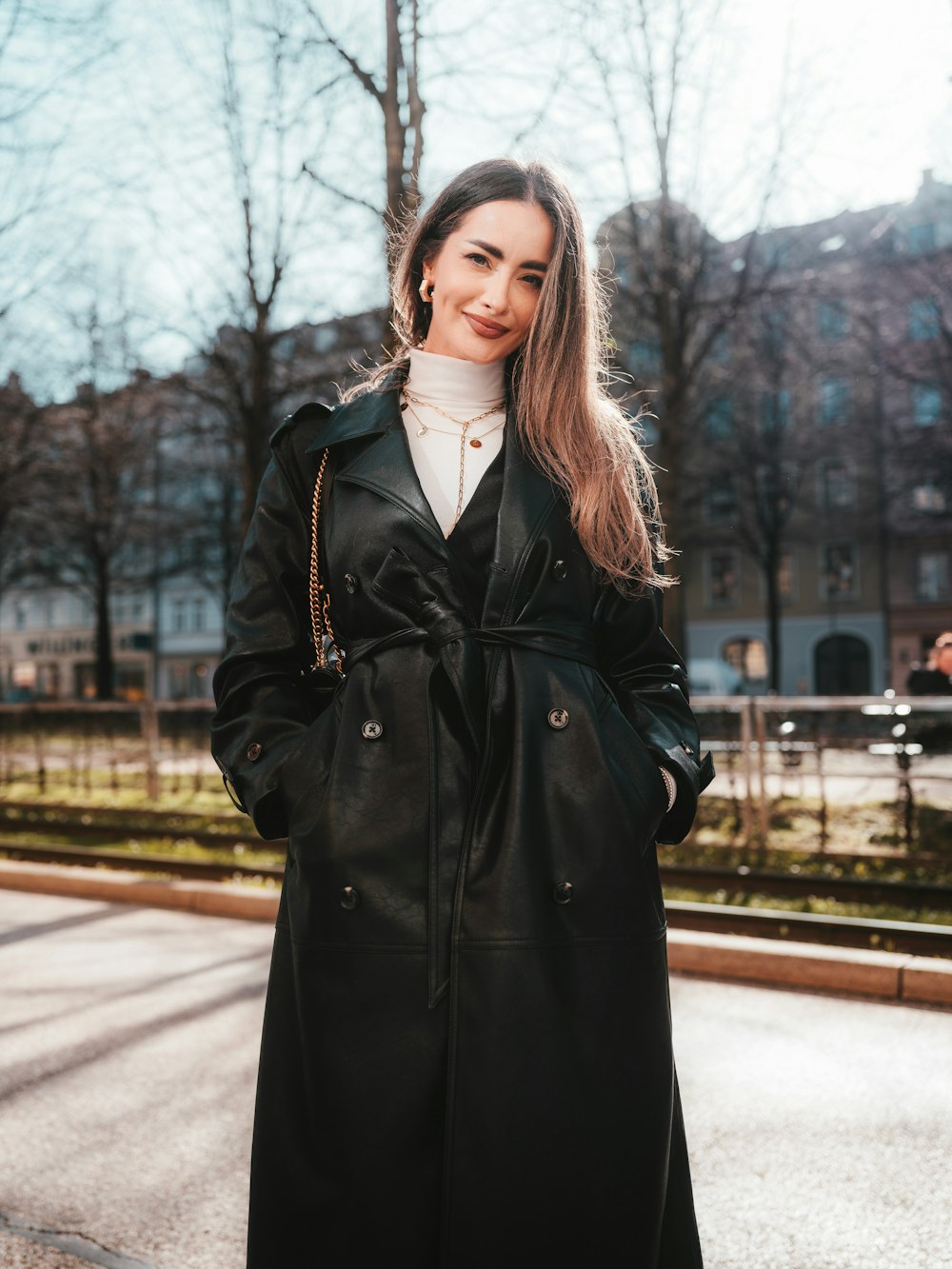 a woman in a black coat is standing on the street