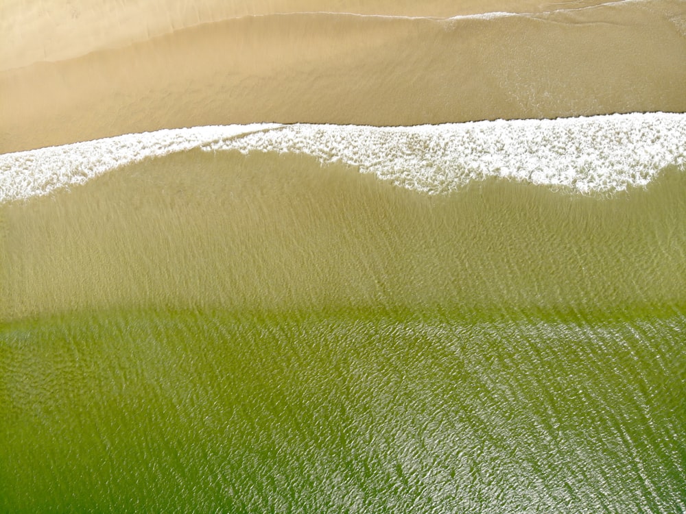 an aerial view of a sandy beach with green water