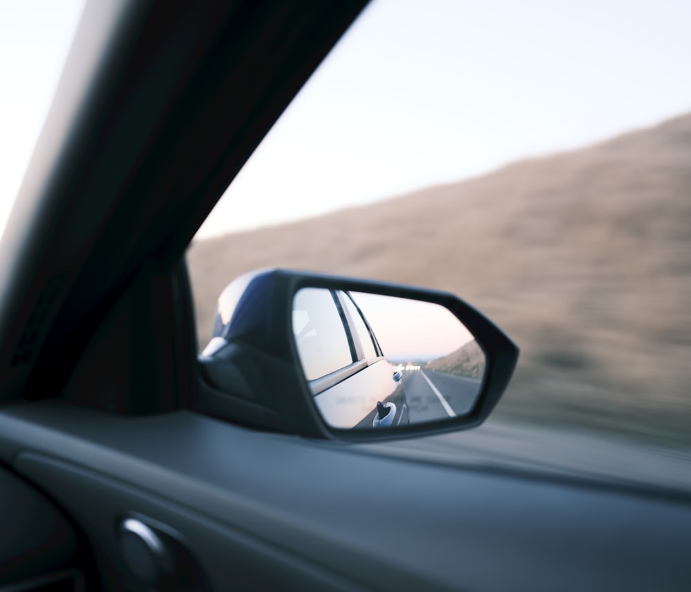 a side view mirror on a car with a mountain in the background