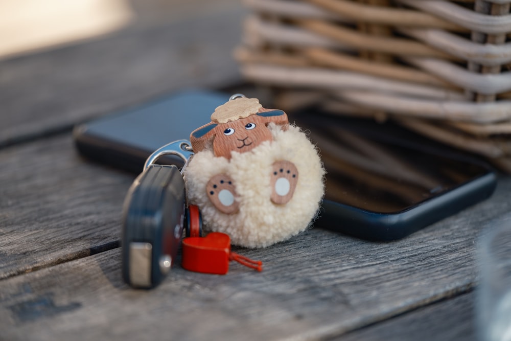 a sheep keychain sitting on top of a table next to a cell phone
