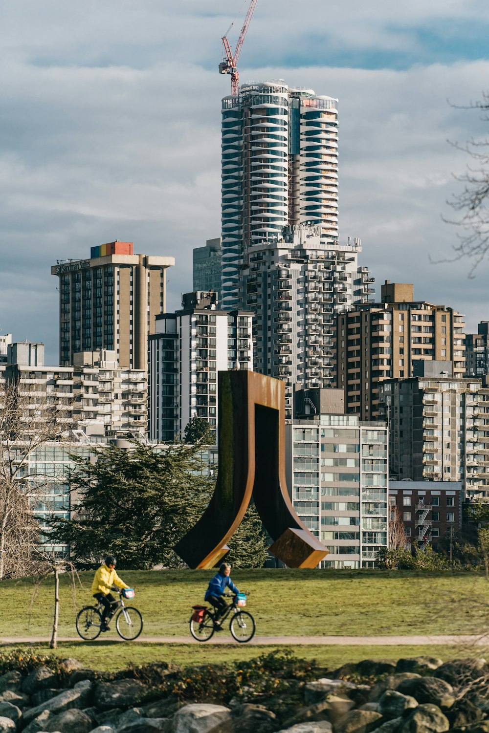 a couple of people riding bikes past a tall building