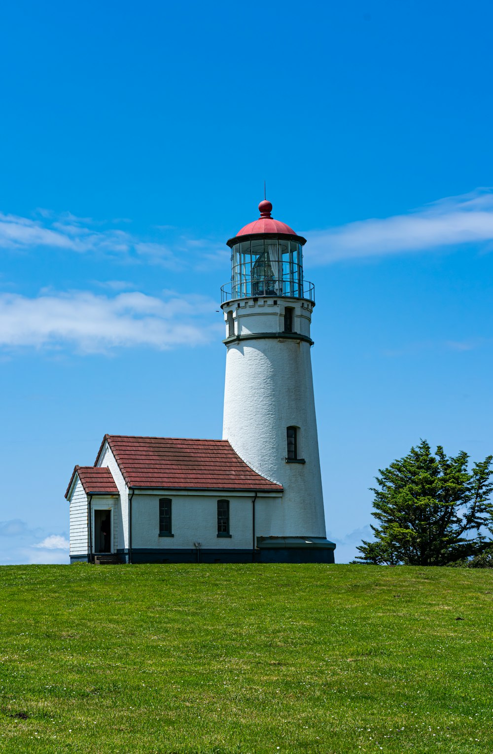 a lighthouse on a grassy hill with a blue sky in the background