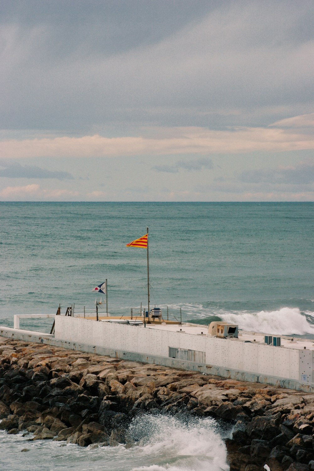 a flag is flying on a pier near the ocean