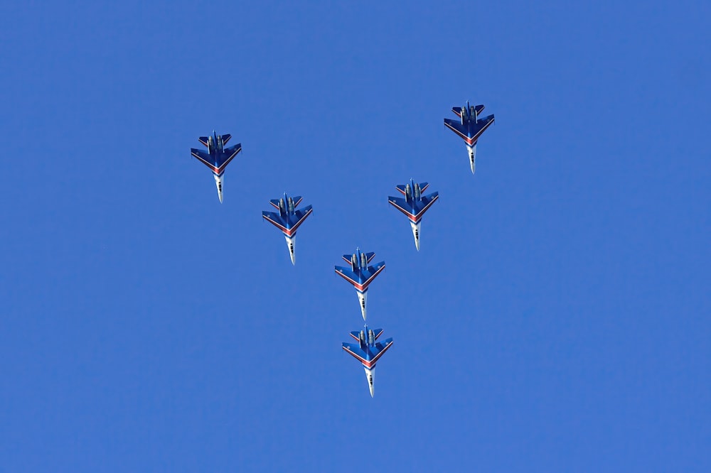 a group of fighter jets flying through a blue sky