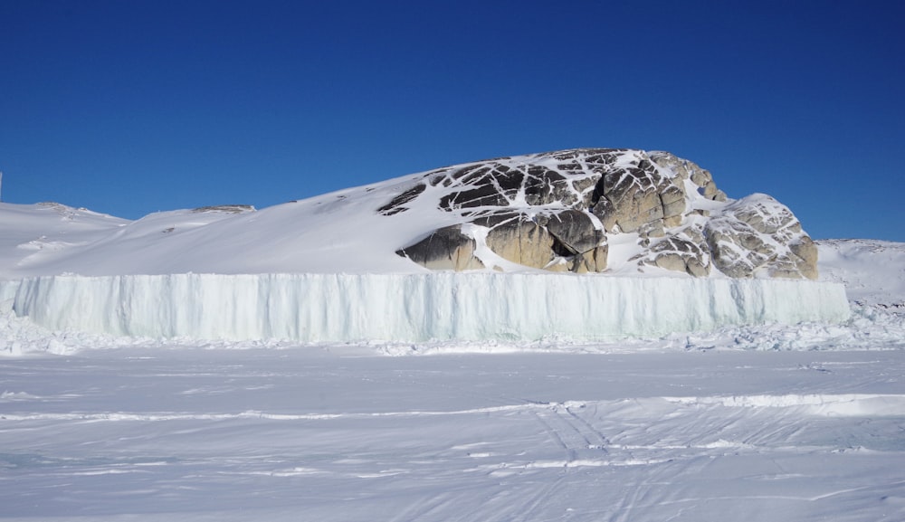 a mountain covered in snow next to a frozen river