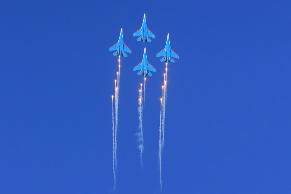 a group of blue fighter jets flying through a blue sky